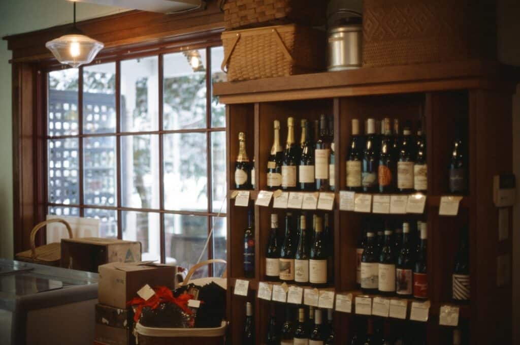 Wine’s Tariff Reckoning: How Trade Policy Is Reshaping What Americans Drink Independent wine shop shelf with European wine bottles and visible price tags in warm lighting