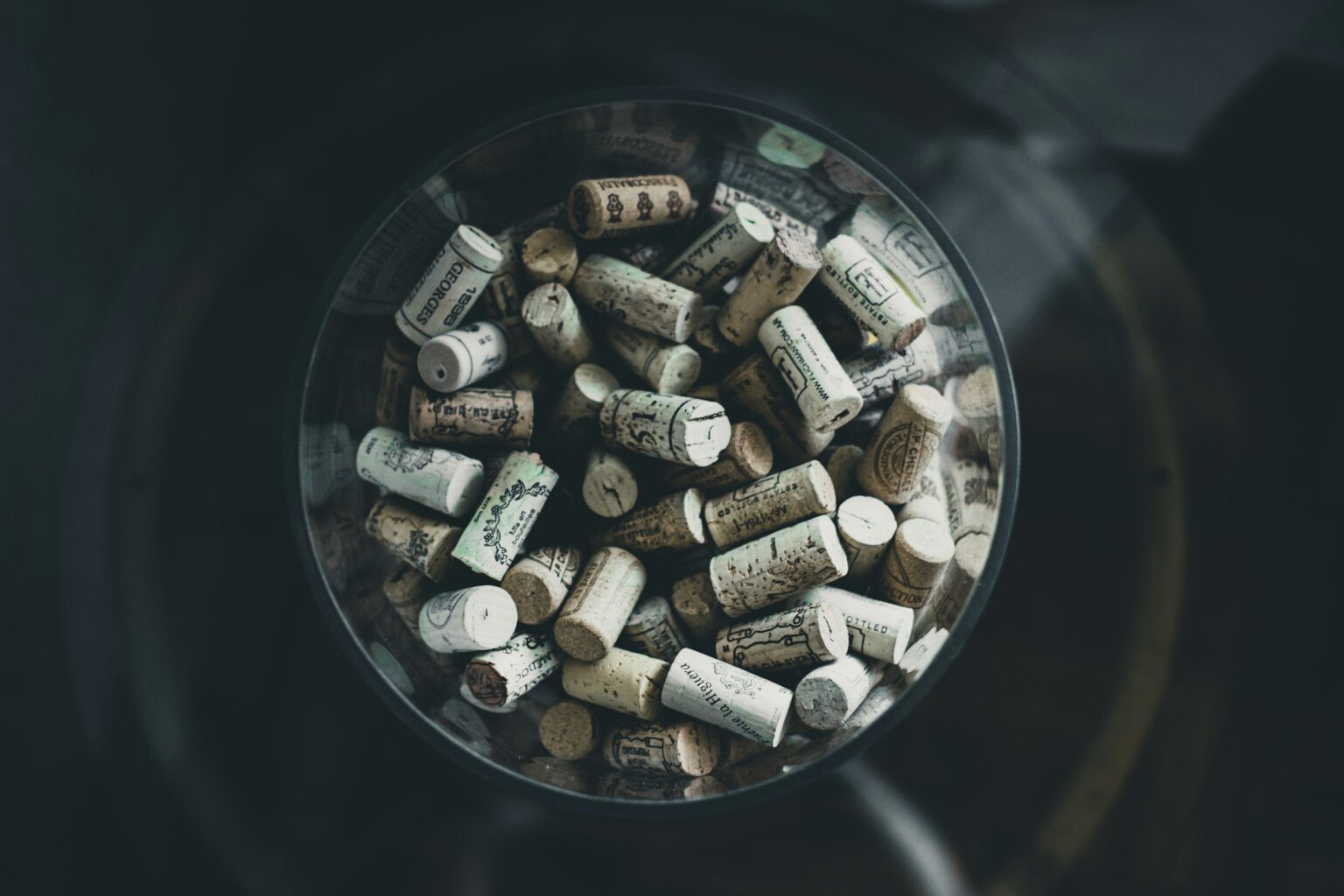 The Closure Truce: How Cork and Screwcap Both Won Top-down view of used natural cork stoppers gathered inside a glass vessel, illustrating the closure truce between cork and screwcap that settled the long-running cork-vs-screwcap debate.