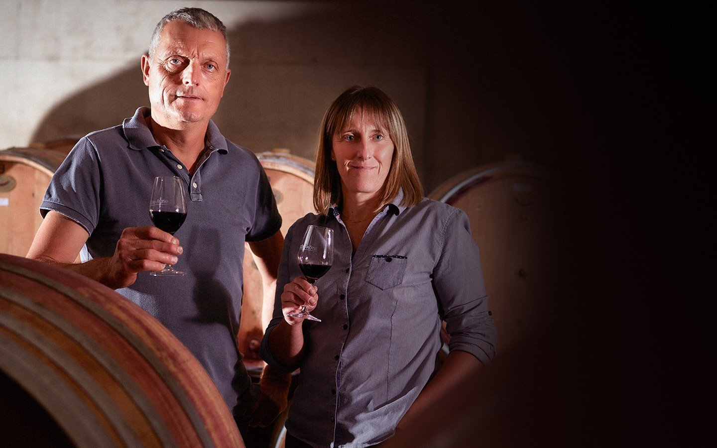 Jean-Paul and Corinne Jamet in the Côte-Rôtie cellar with barrels behind them.