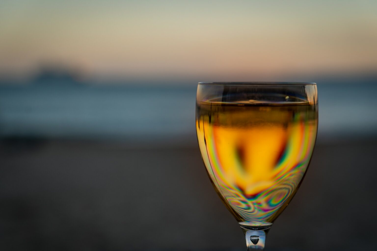 The Jura Comeback: Savagnin, Vin Jaune, and Why Sommeliers Are Pouring the Mountain Whites A glass of deep-golden Jura Vin Jaune backlit by low evening sun, the oxidative color built over years aging under a veil of yeast.