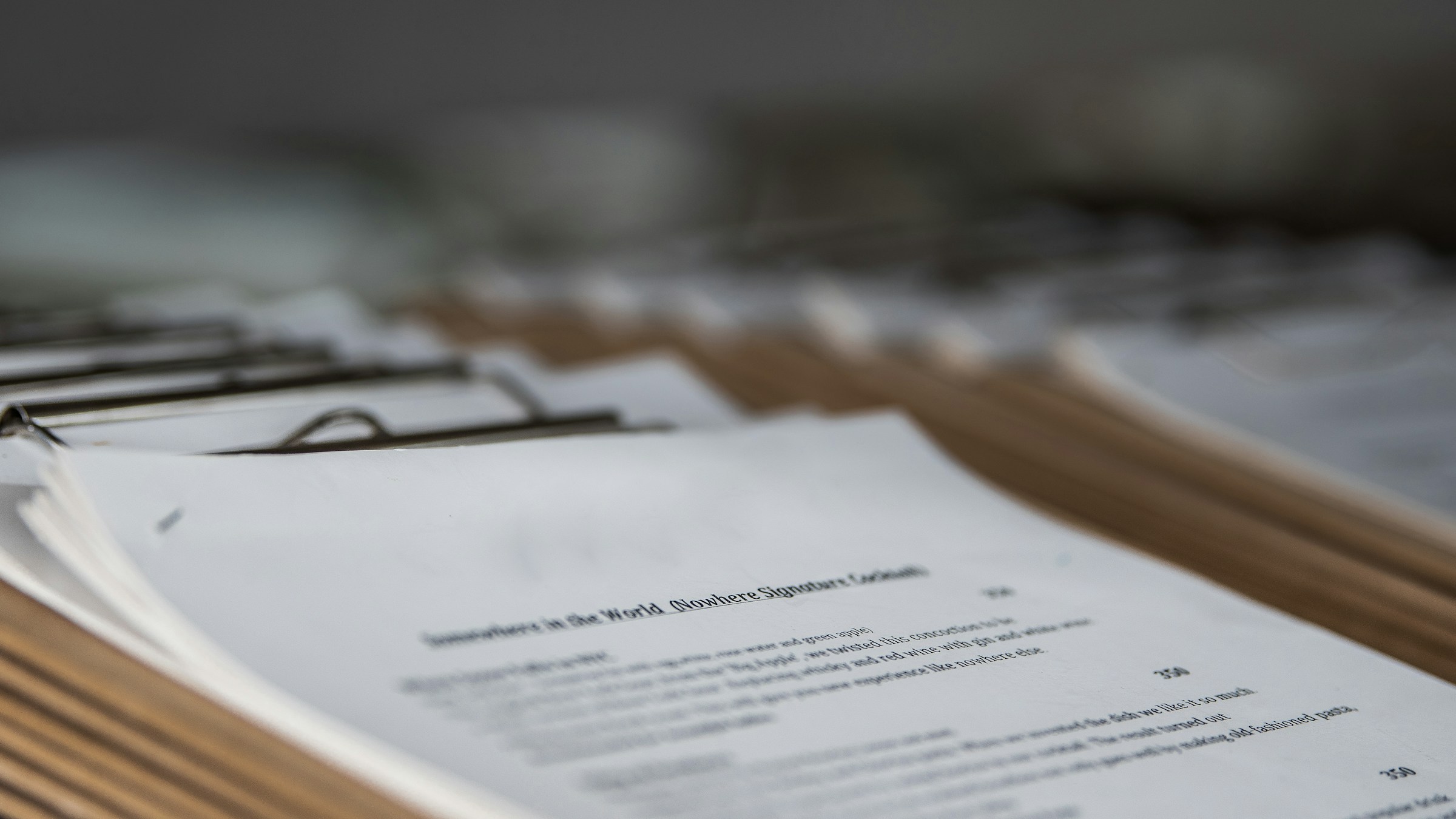 A row of restaurant menus on wooden clipboards in shallow focus, the foreground page legible
