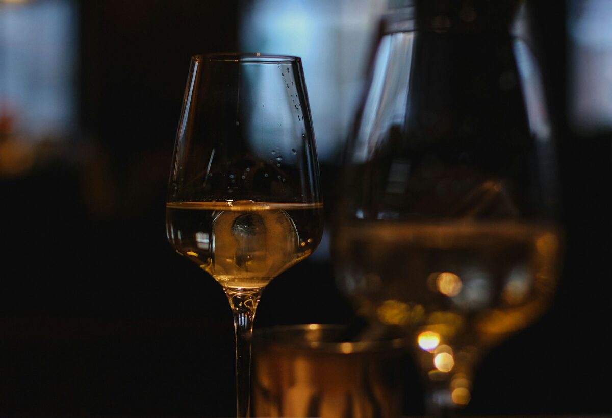 A glass of pale gold wine glowing in low light
